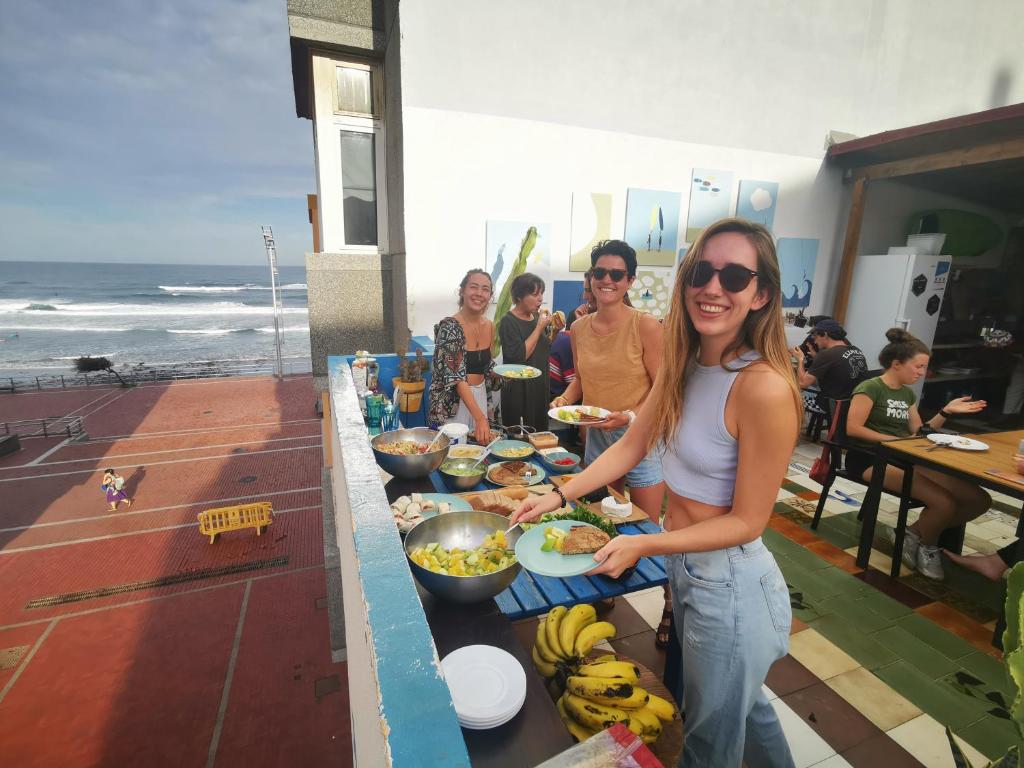 a woman standing in front of a buffet of food at La Ventana Azul Surf Hostel in Las Palmas de Gran Canaria