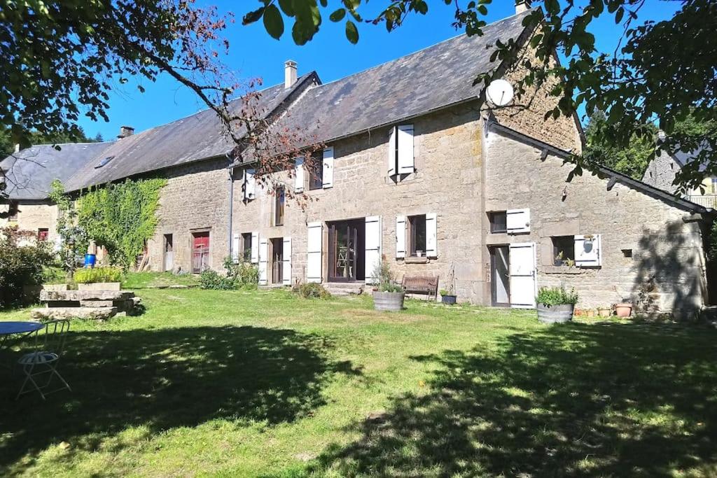 une ancienne maison en pierre avec une cour herbeuse dans l'établissement Belle Longere de 10 couchages - lac de vassiviere, à Beaumont