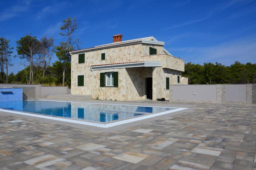 a stone house with a swimming pool in front at Apartments Sana 2 in Vir