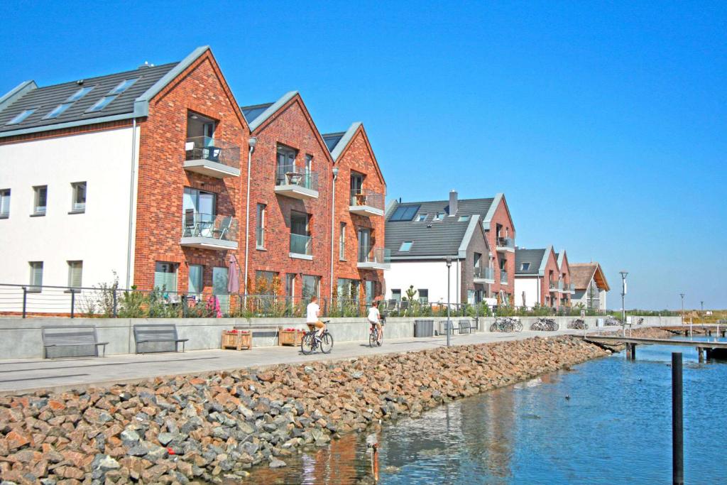 a man riding a bike on a sidewalk next to houses at Yachthafenblick in Heiligenhafen