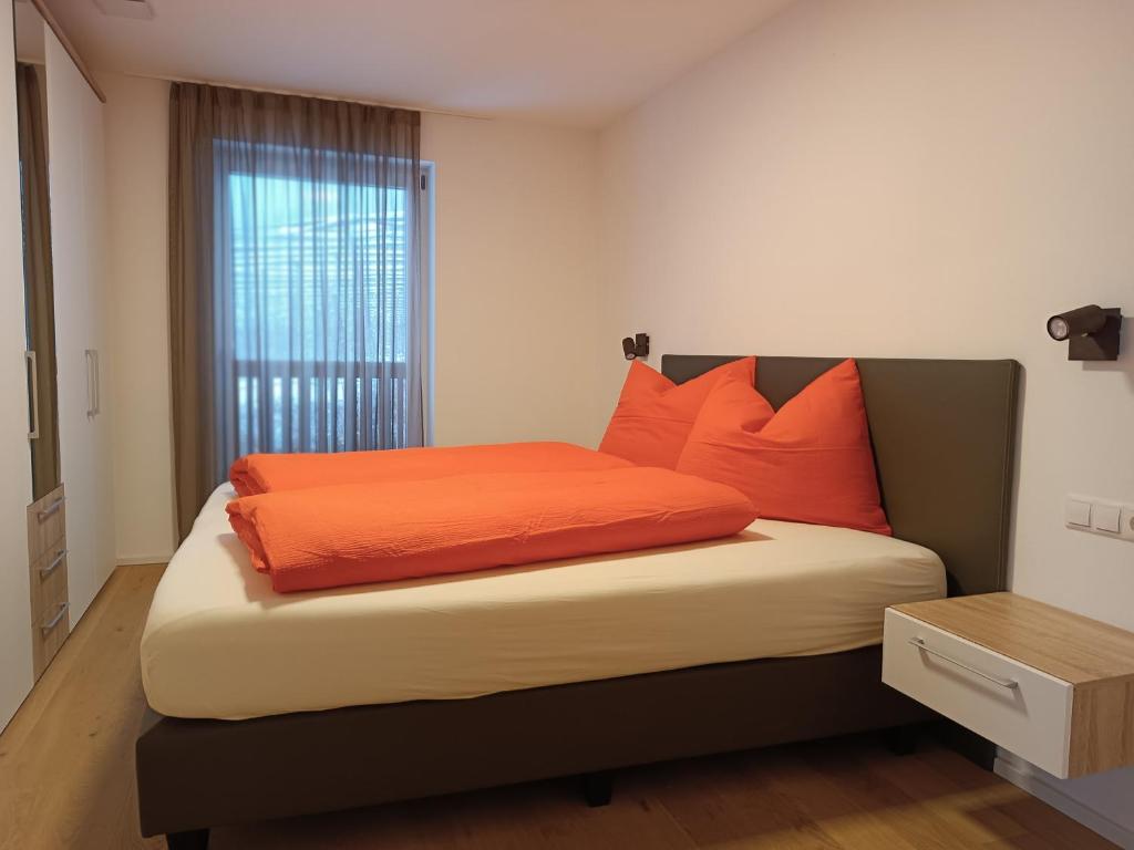 una camera da letto con un letto con cuscini arancioni e una finestra di Zum Lindenwirt - Al Tiglio a Naz-Sciaves