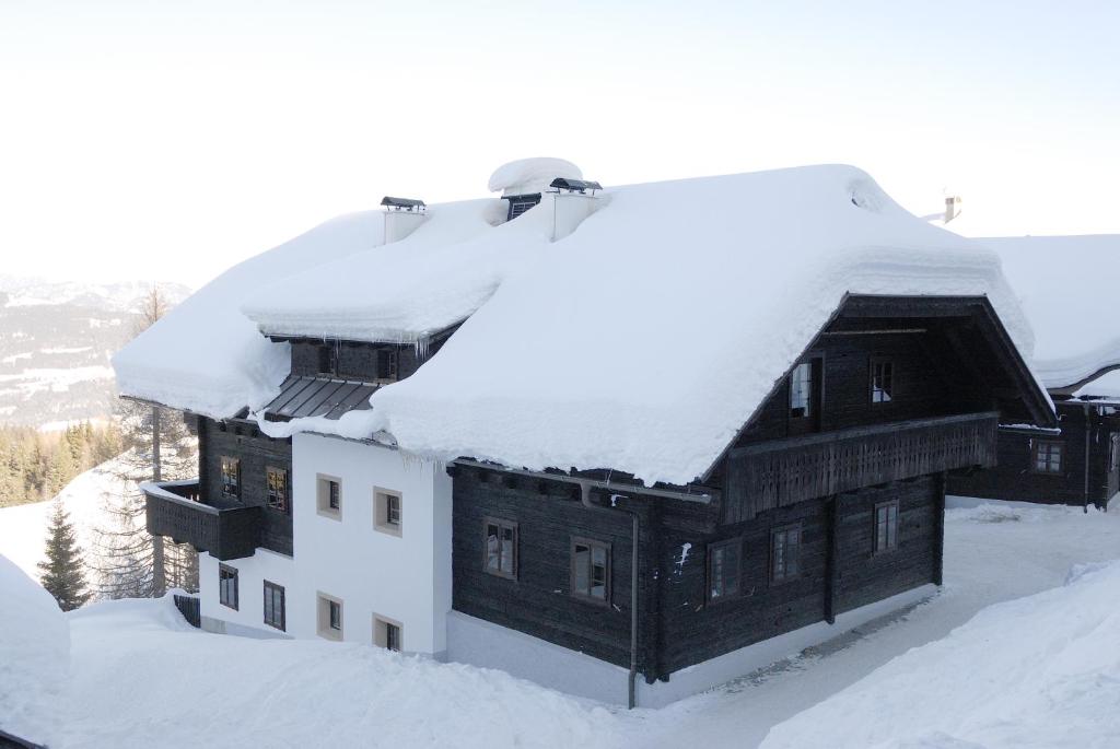 a building covered in snow with snow on the roof at Alpenhäuser Marcius in Sonnenalpe Nassfeld