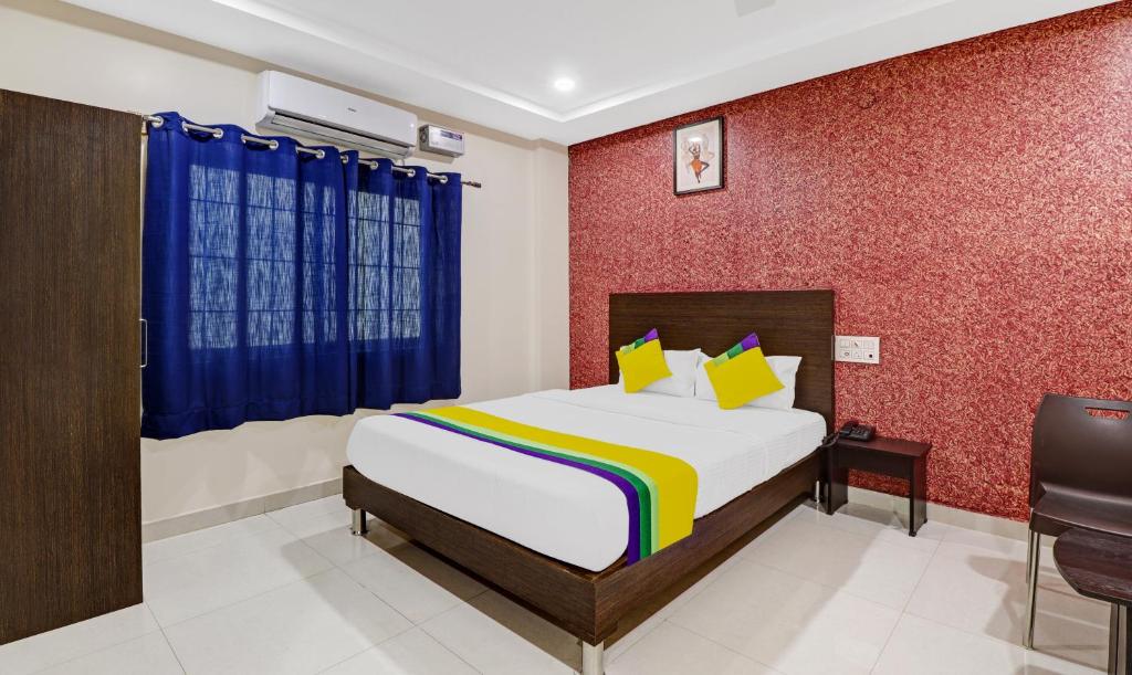 a bedroom with a bed and a red wall at Itsy By Treebo - Harsha Comforts in Chikmagalūr