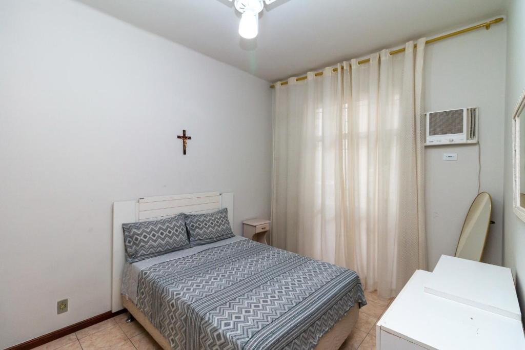 ein Schlafzimmer mit einem Bett und einem Kreuz an der Wand in der Unterkunft Copacabana Apartamento - Ouro in Rio de Janeiro