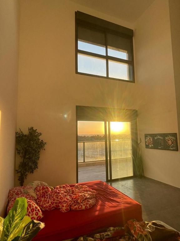 1 dormitorio con cama roja y ventana en פנטהוז ונוף עוצר נשימה, שקט אפשרות בקומה העליונה לחדר משרד הפנטהוז מיועד לאורחים, en Bet Shemesh