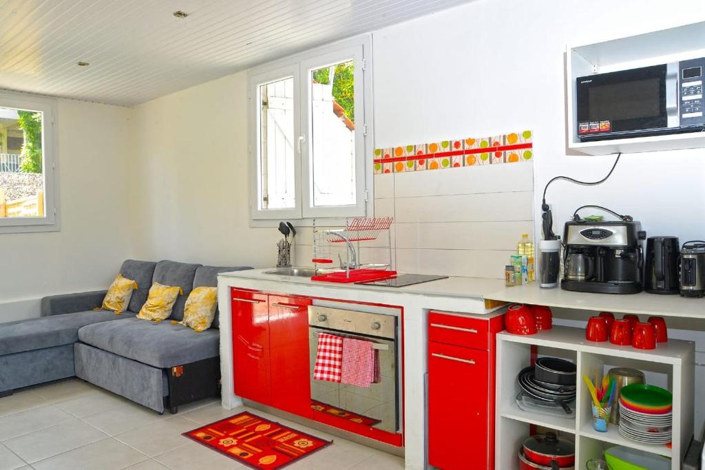 a kitchen with red cabinets and a couch in a room at Résidence Flores De Maria in Le Marin