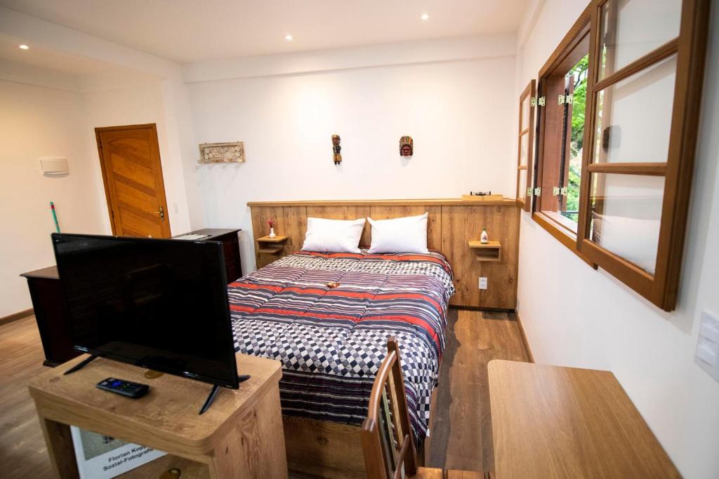 1 dormitorio con 1 cama y TV de pantalla plana en Casa Lucas - loft espaçoso com jardim e churrasqueira, en Petrópolis