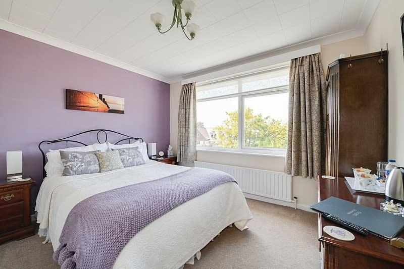 a bedroom with a large bed and a window at The Coast Yard B & B and Garden Chalets in Selsey