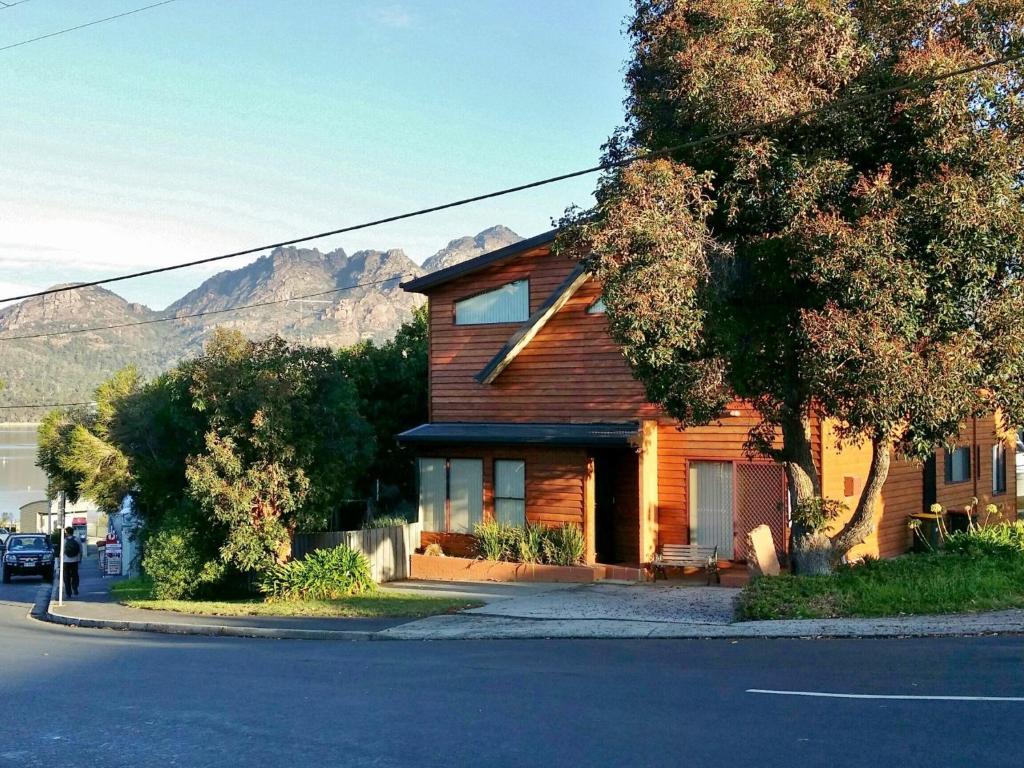 a wooden house on a street with mountains in the background at Freycinet Sands in Coles Bay