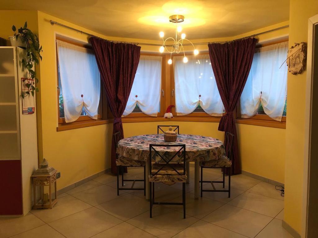 a dining room with a table and some windows at casa Olivieri in Carisolo