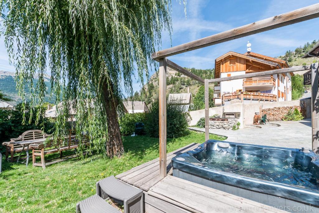 a hot tub in the yard of a house at Luxury Chalet with outdoor Hot Tub, Sauna, Gardens & Mountain Views! in Briançon