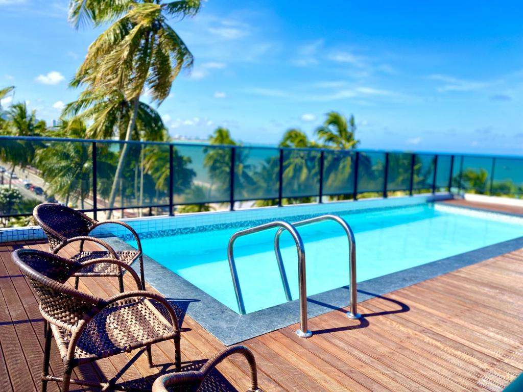 una piscina en un balcón con sillas y el océano en IMPERIAL SUÍTES Flat - Cabo Branco by PenareiaTurBr, en João Pessoa