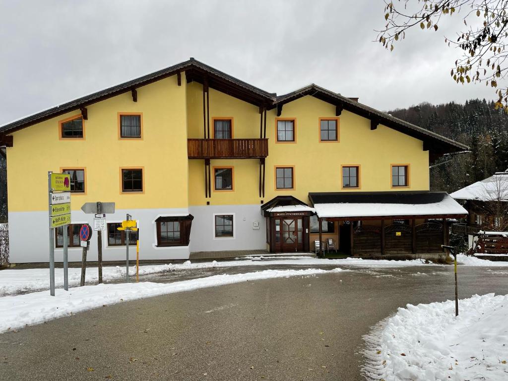 a large yellow building with snow on the ground at Hotel Ötscherblick in Lackenhof