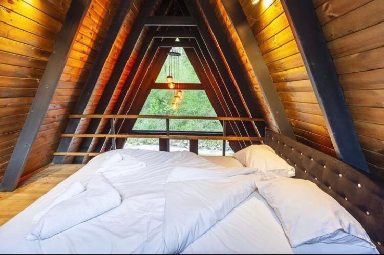 a bed in a room with a large window at Özlifesapanca Bungalow in Sapanca