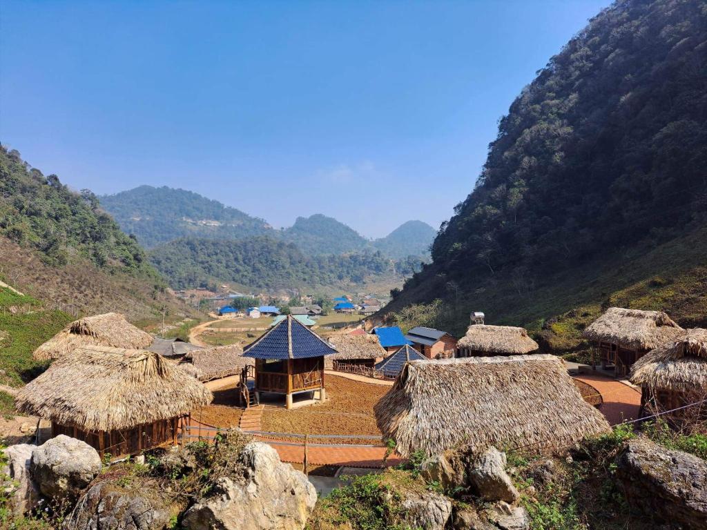 a group of houses with thatched roofs on a mountain at Homestay Highland Hmong in Hòa Bình