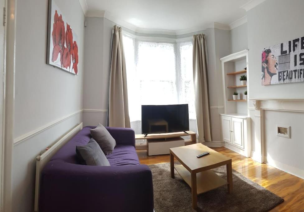 a living room with a purple couch and a tv at London. Gorgeous 2 bed flat near Olympic Park. in London