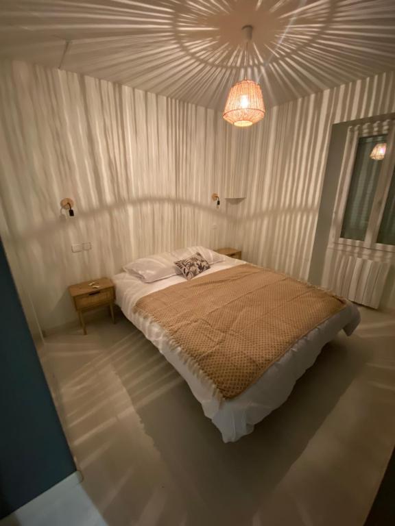 1 dormitorio con cama y lámpara de araña en La Petite Maison Blanche, 