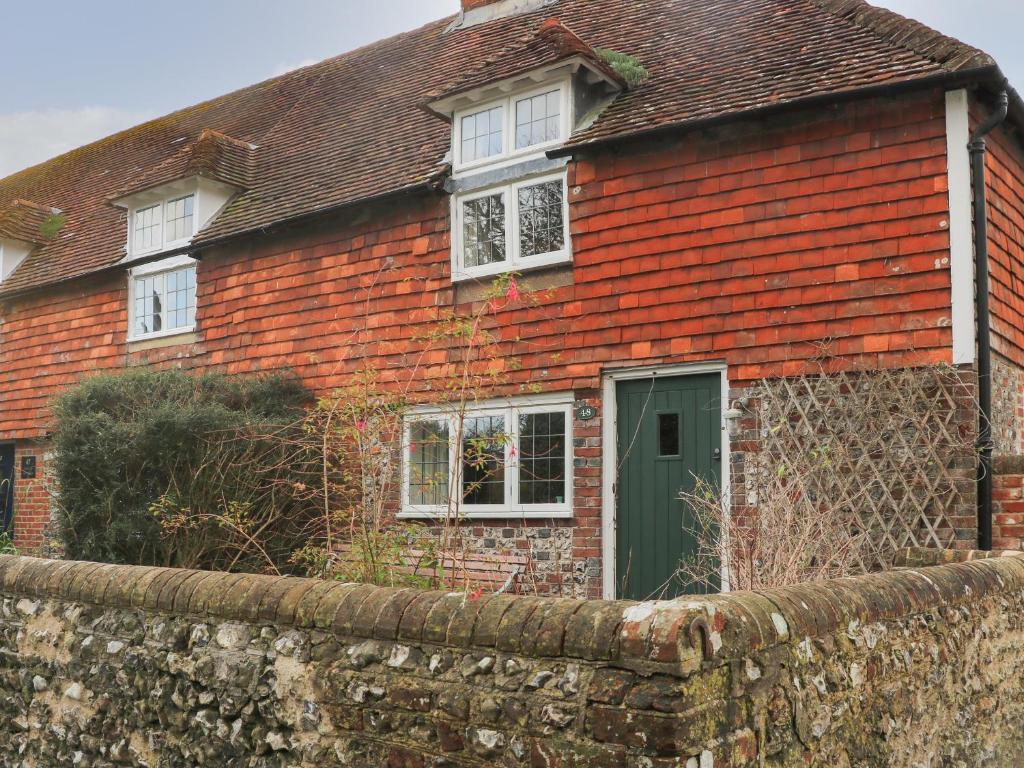 a brick house with a green door and a stone wall at 48 Polecat Cottages in Lewes