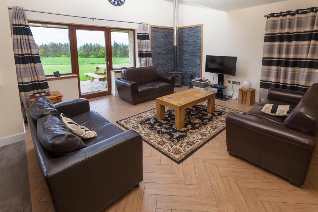 a living room with leather furniture and a television at 1 Eden at Williamscraig Holiday Cottages in Linlithgow