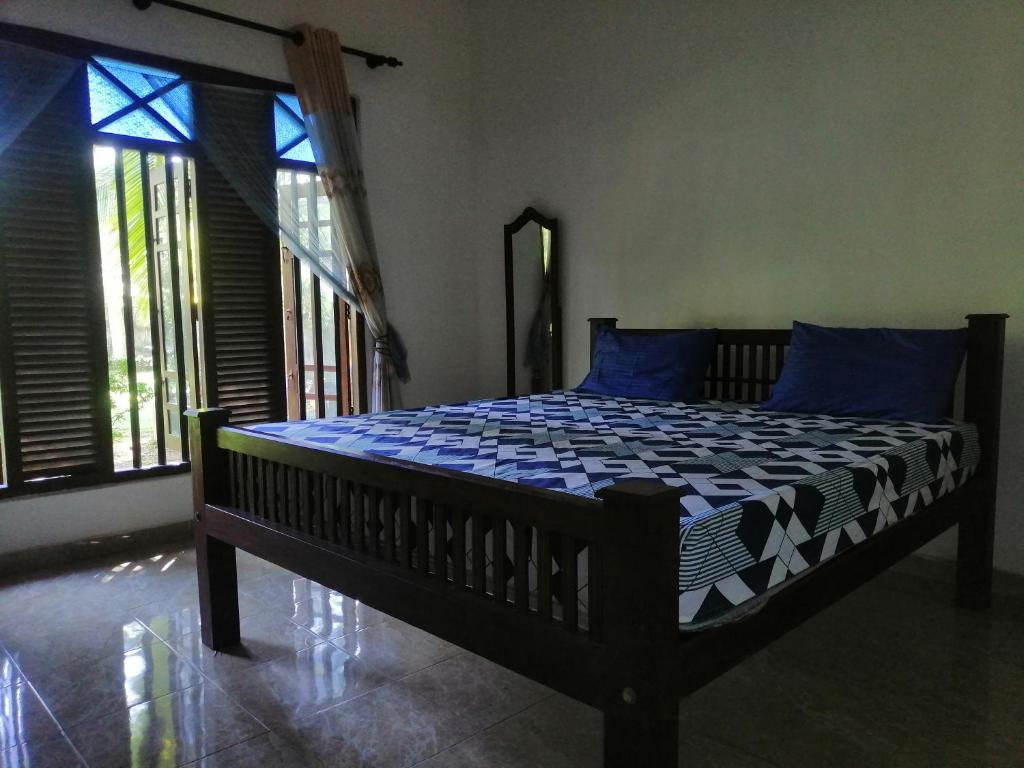 Schlafzimmer mit einem Bett mit blauen Kissen und Fenstern in der Unterkunft The Madampa Village Side Lodge in Ambalangoda