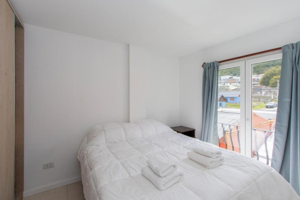 a bedroom with a bed with two towels on it at Gray Fox Apartments Alem in Ushuaia