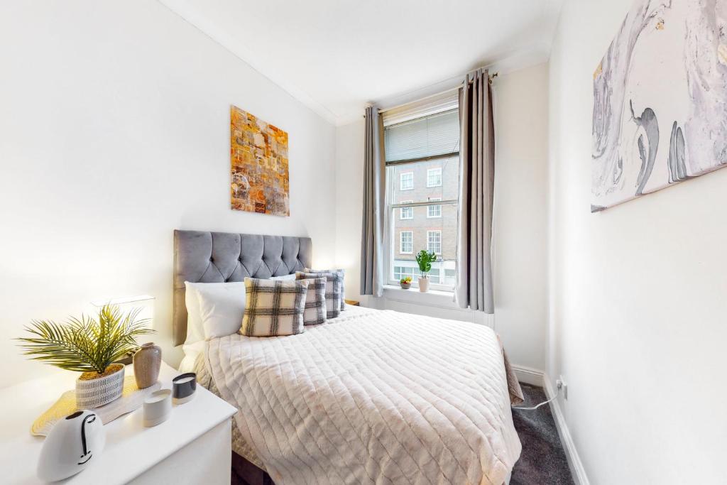 a white bedroom with a bed and a window at Park Lane Apartments Marble Arch in London