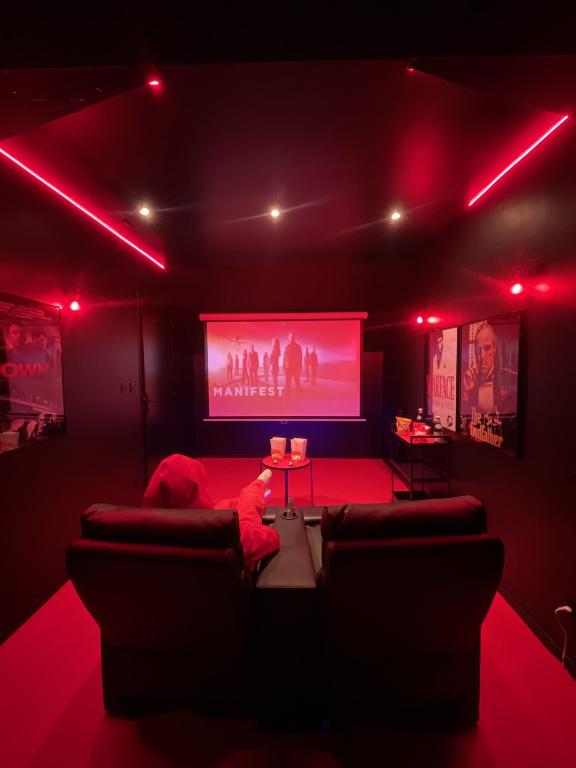 Suite cinéma et jacuzzi privé في مولان: غرفة معيشة فيها انارة حمراء وشاشة كبيرة