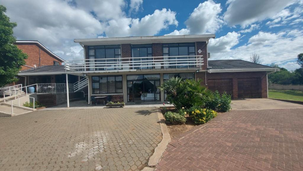 a large house with a balcony on a brick driveway at Skylight Guest House in Harrismith