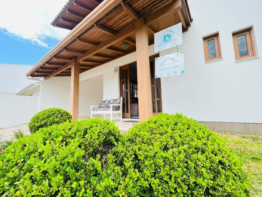 une maison avec une terrasse couverte entourée de buissons. dans l'établissement Casa da Praia Pousada - Guesthouse, à Torres