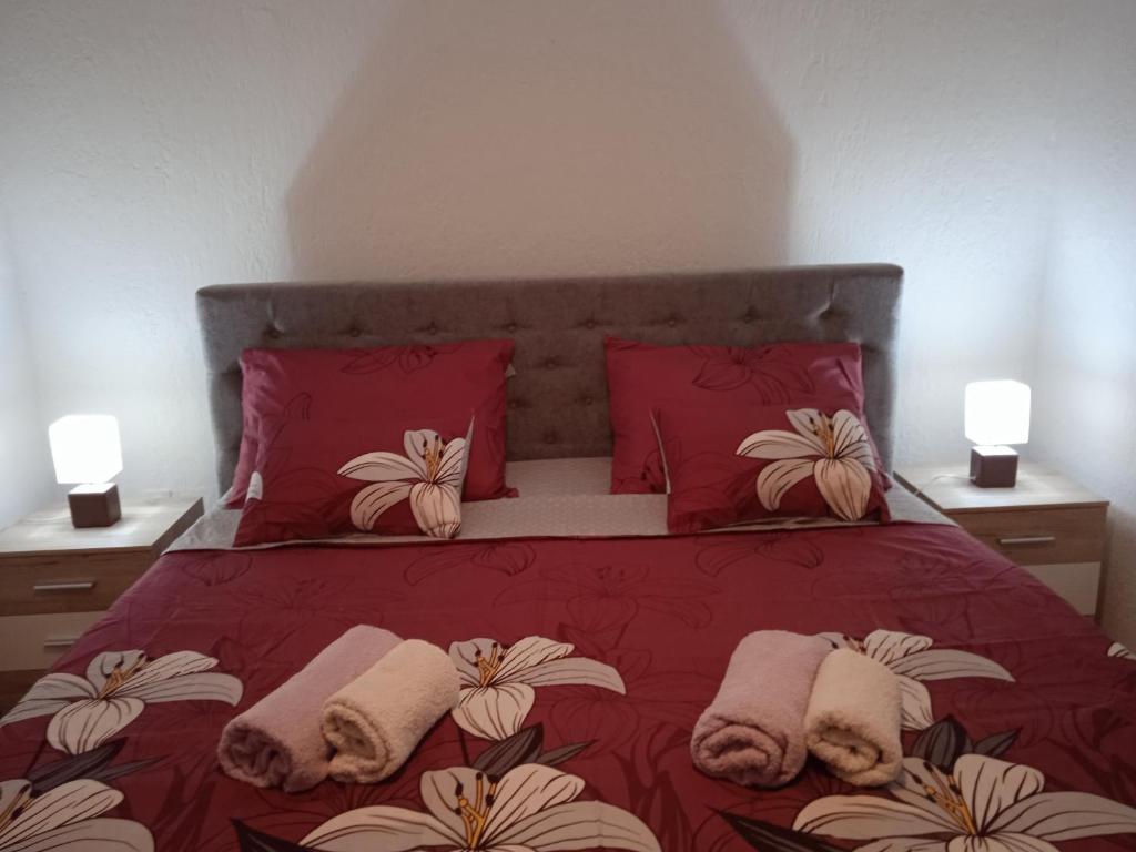 a bedroom with a red bed with pillows and two lamps at Apartment Fortica in Senj
