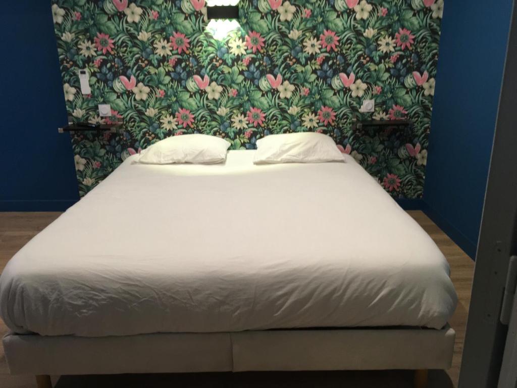 uma cama num quarto com papel de parede floral em Appartements Nice Centre Carré d’or em Nice