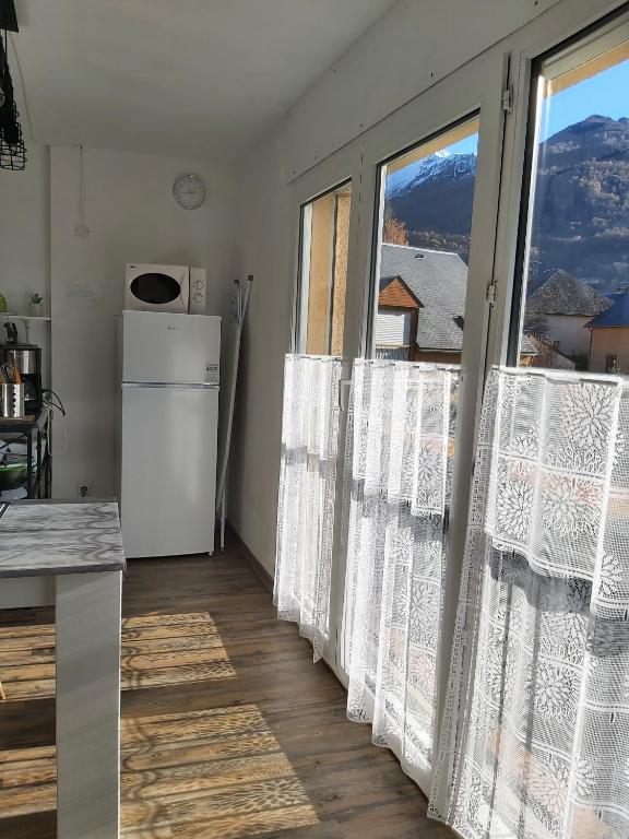a kitchen with white curtains and a refrigerator at Luz St Sauveur, Appartement 3 personnes, vue montagne, exposé sud, Résidence très calme in Luz-Saint-Sauveur