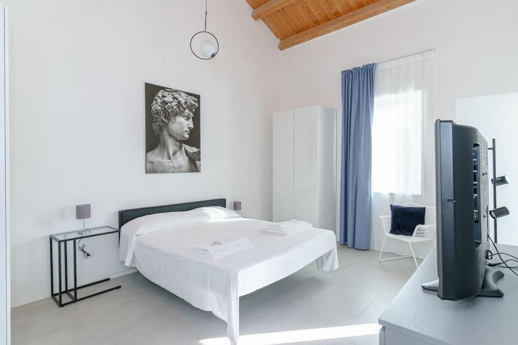 um quarto branco com uma cama e uma secretária com um monitor em Casa Ancora TownHouse em Catânia