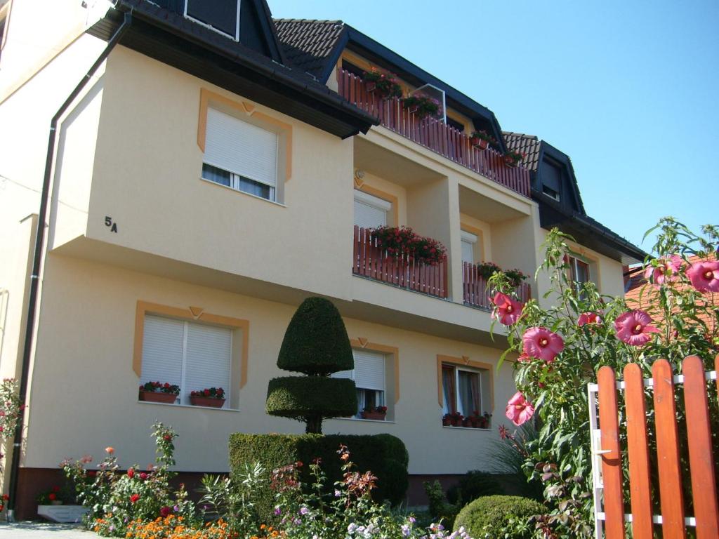 a building with a fence and flowers in front of it at Judit Vendégház in Hévíz