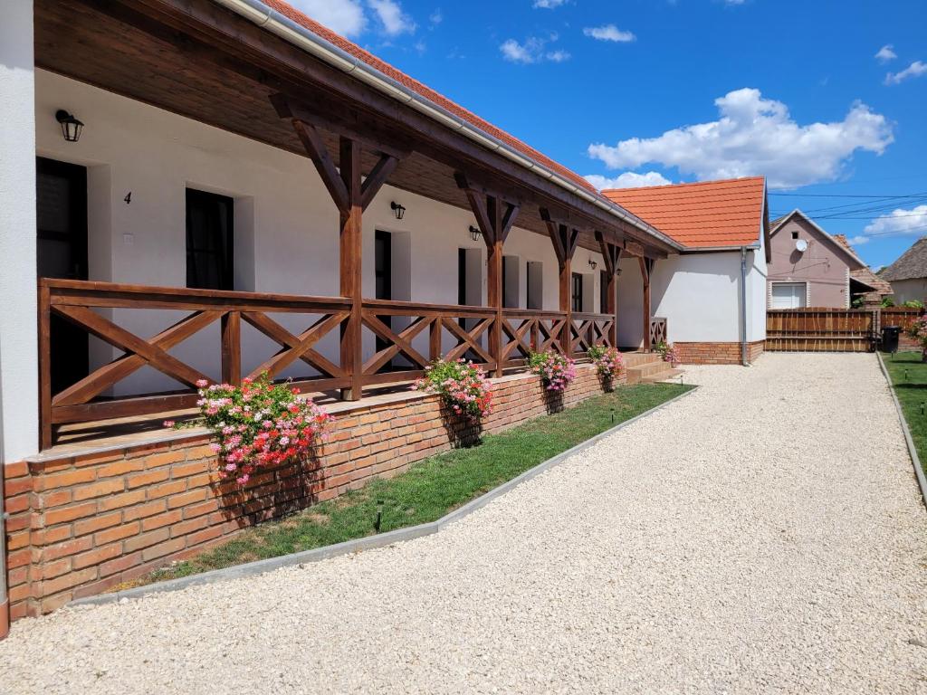 a building with a wooden fence and some flowers at Végvári Vendégház in Magyarbóly