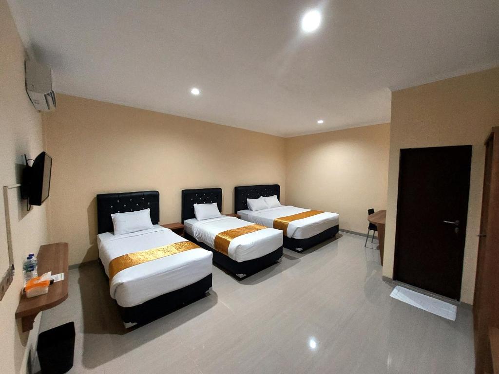 a hotel room with two beds and a flat screen tv at Harmony Inn Belitung - City Hotel in Tanjungpandan