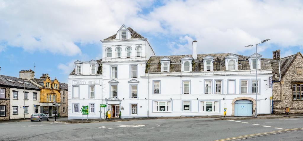 a large white building with a tower on a street at County Hotel in Kendal