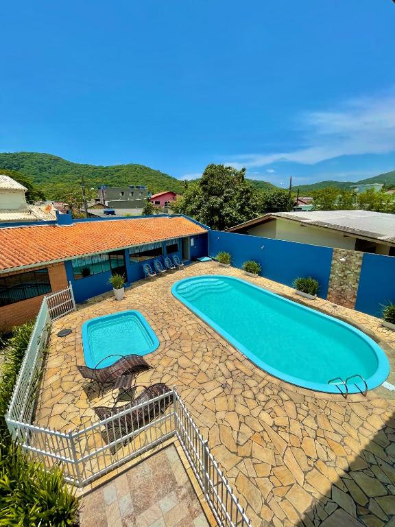 a large swimming pool with two chairs and a building at Encanto Parque Pousada in Penha