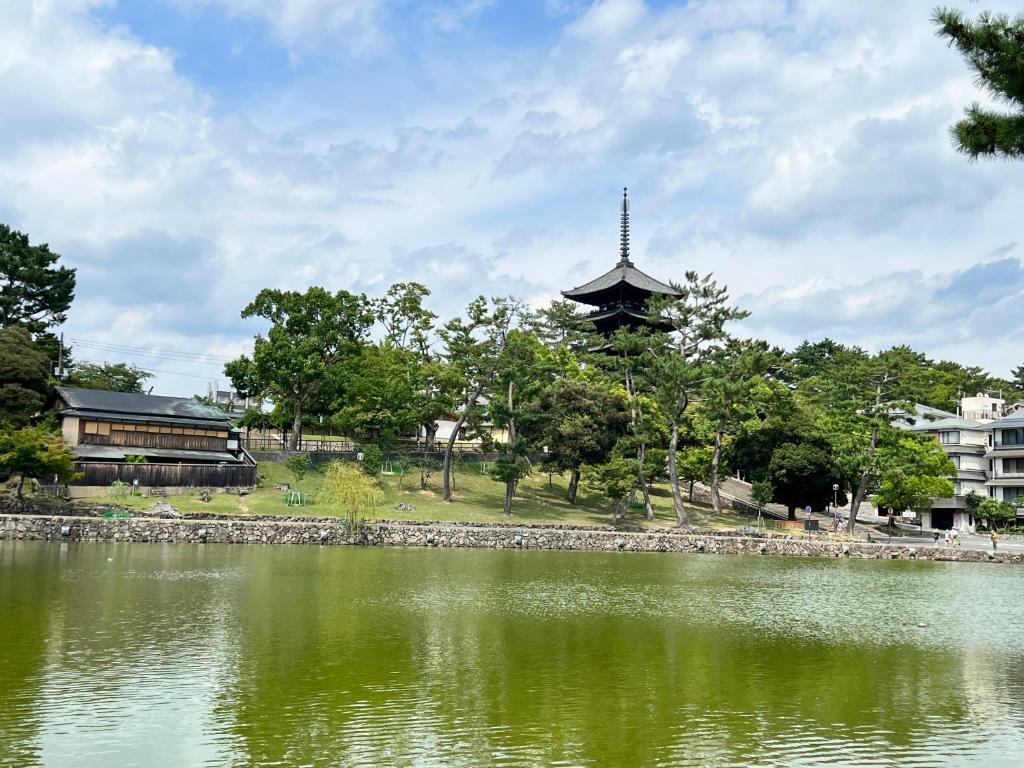 una pagoda di fronte a un lago con un edificio di Old modern house in Nara Second a Nara