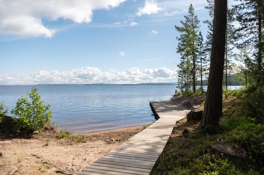 un chemin en bois menant à l'eau sur une plage dans l'établissement Sinikallio | Paajoen Vuokramökit, à Himos