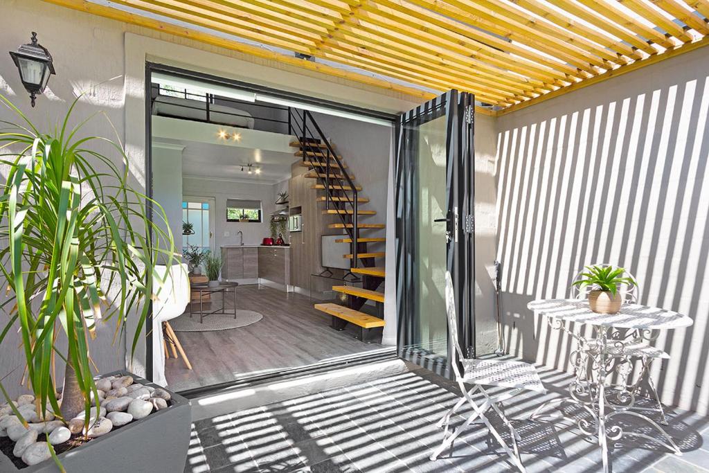 Blouberg Studio Apartment في بلوبيرجستراند: فناء به درج وطاولة بها نباتات