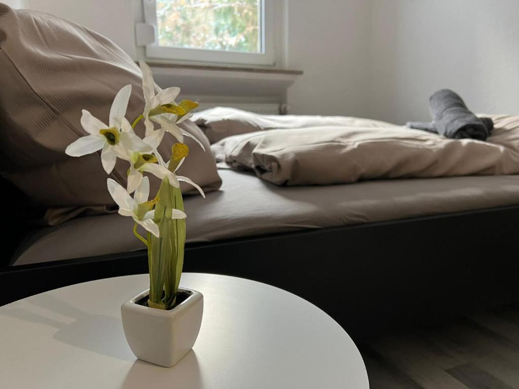 una flor blanca en un jarrón blanco sobre una mesa en Schönes einfaches Zimmer in Oldenburg 109 en Oldenburg