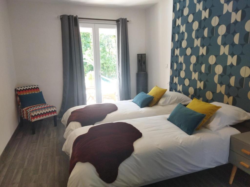 two beds in a room with a window at Le Mas Victoria - Chambres d'hôtes avec table d'hôtes-Parking privé ferme in Carcassonne