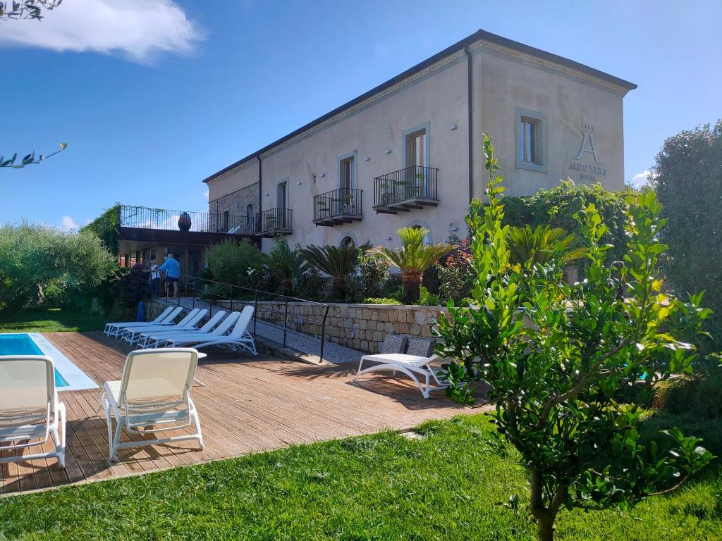 - un bâtiment avec des chaises et une piscine à côté d'une maison dans l'établissement Alimunera, à CastellʼUmberto