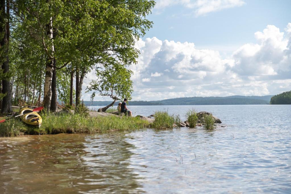 una persona sentada en la orilla de un lago en Suvituuli | Paajoen Vuokramökit, en Himos
