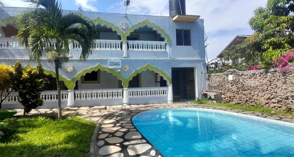 a villa with a swimming pool in front of a house at Villa tuffah in Watamu