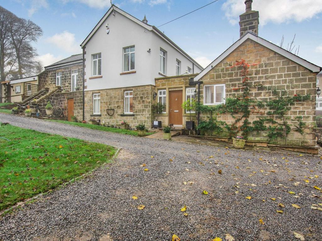 an old brick house on a gravel road at Clarion Lodge Cottage Ilkley in Menston