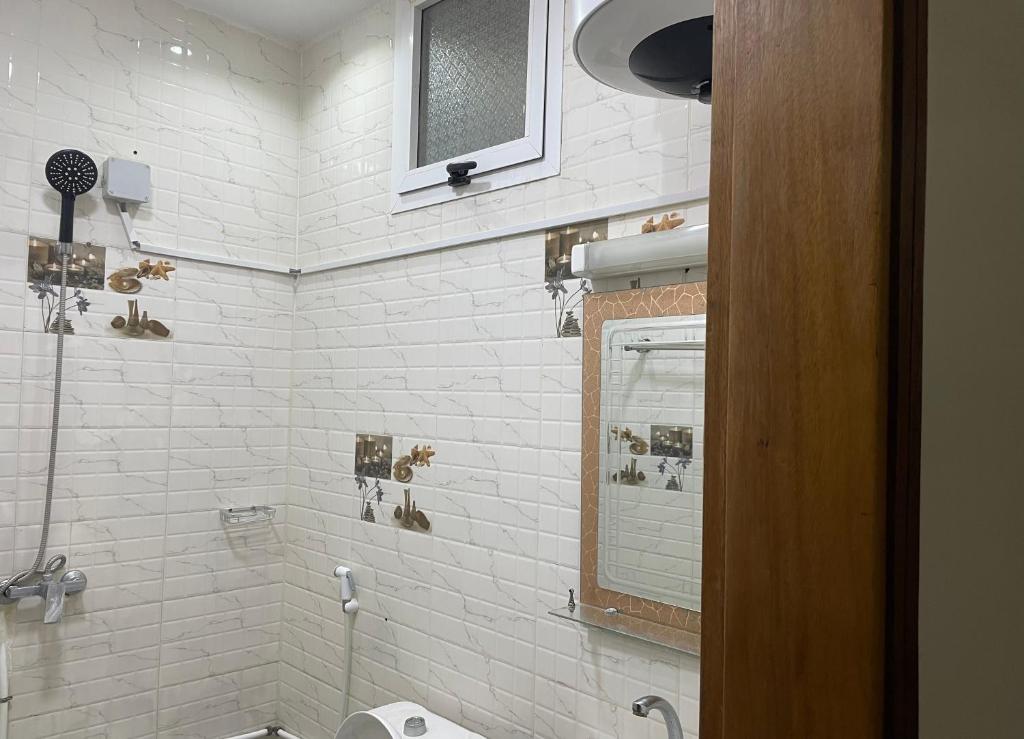 GHEST HOUSE BASS في داكار: حمام من البلاط الأبيض مع حوض ومرآة