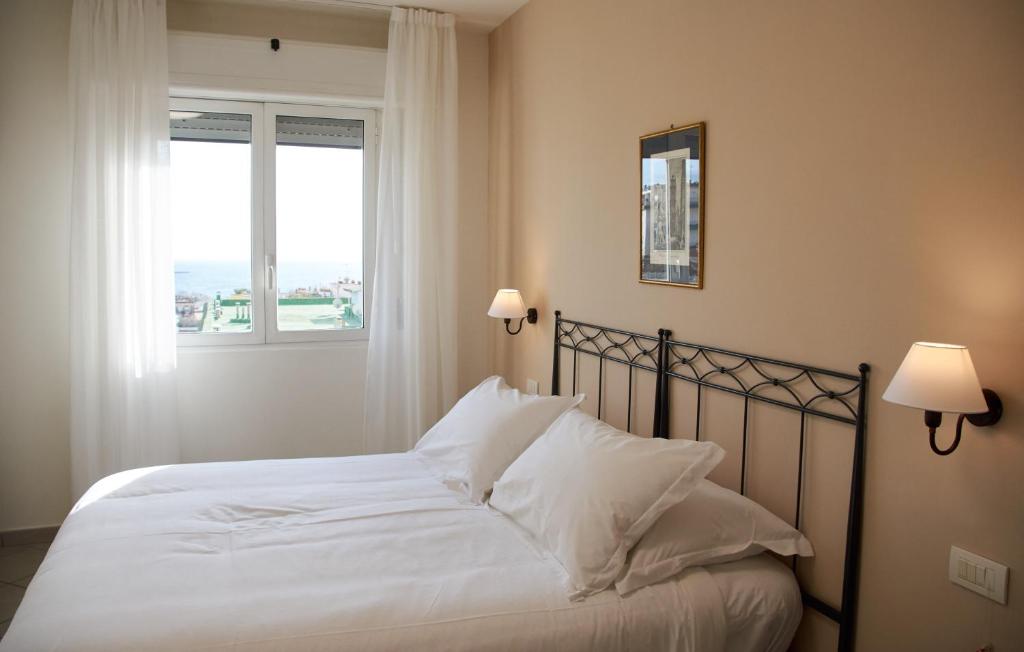 Schlafzimmer mit einem Bett mit weißer Bettwäsche und einem Fenster in der Unterkunft Villa Margherita in Neapel