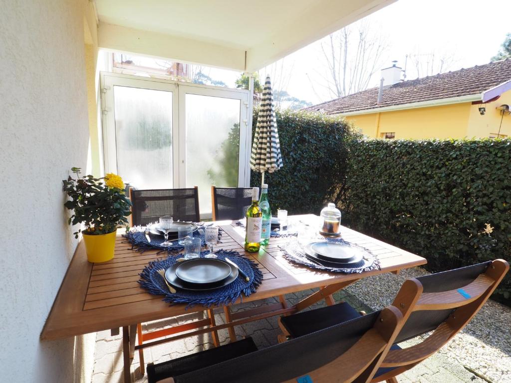 - une table en bois avec des assiettes et de la vaisselle dans l'établissement T2 Arcachon, Jardin Terrasse, Proche Plage, Parking Privé - FR-1-474-75, à Arcachon